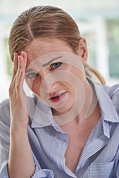 Portrait Of Stressed Businesswoman Suffering With Headache In Office