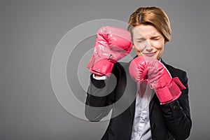 stressed businesswoman in suit and pink boxing gloves