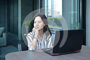 Stressed Casual Business Asian Woman thinking in front of lapto