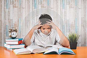 Stressed college student learning hard with books in exams preparation feeling overwhelmed, depressed and exhausted