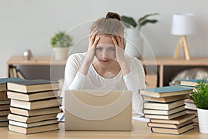 Stressed college student tired of hard learning with books laptop