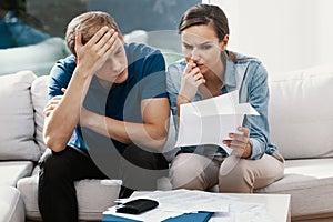 Stressed couple looking frustrated, having no money to pay off their debts, managing family budget together