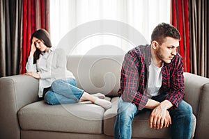 Stressed couple sitting on couch, family conflict