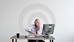 Stressed crazy businessman breaking a keyboard on his monitor in the office. The man has problems at work and