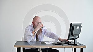 Stressed crazy businessman breaking a mug on his computer in the office. The man has problems at work and frustration.