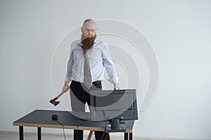 Stressed crazy businessman smashing his computer in office using ax problem concept. The man has problems at work and