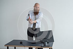 Stressed crazy businessman smashing his computer in office using ax problem concept. The man has problems at work and