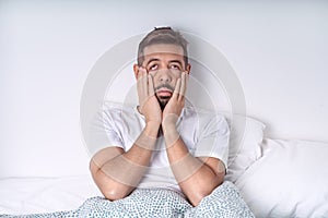 Stressed and depressed man lying in the bed. Bad mood and bad morning.