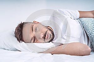 Stressed and depressed man lying in the bed. Man feeling bad, desperate and helpless