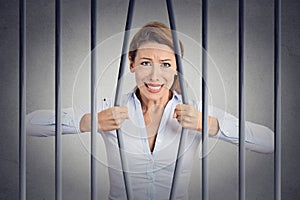 Stressed desperate angry businesswoman bending bars of her prison