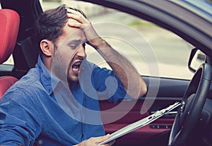 Stressed desperate man driver with papers sitting inside car