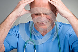 Stressed doctor with hands on head, wearing surgical mask and stethoscope.