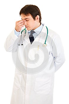 Stressed doctor holding fingers at noseband