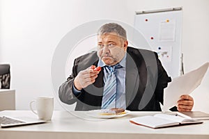 Stressed employee stuffing himself with baked sweets