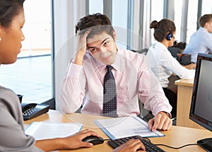 Stressed Employee Working In Busy Office