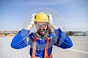 Stressed engineer grab his head suffer from acrophobia while working on the factory rooftop