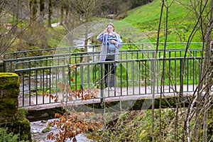 Stressed, exhausted and depressed woman standing on a bridge with her little baby