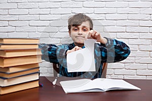 Stressed and exhausted schoolboy tearing papers sitting at the d