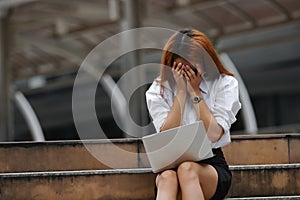 Stressed exhausted young Asian business woman with hands on face feeling disappointed or tired with job.