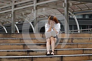 Stressed exhausted young Asian business woman with hands on face feeling disappointed or tired with job.