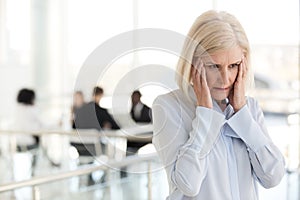 Stressed fatigued mature businesswoman suffer from headache in o