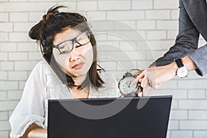 Stressed female Asian worker sitting at desk feeling pressure from annoying boss