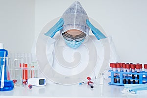 Stressed female doctor sitting tired at his desk. Mid adult female doctor working long hours in protective clothes