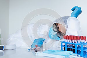 Stressed female doctor sitting tired at his desk. Mid adult female doctor working long hours in protective clothes