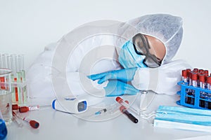 Stressed female doctor sitting tired at his desk. Mid adult female doctor working long hours in protective clothes