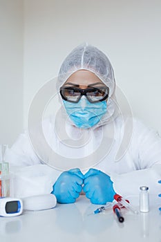 Stressed female doctor sitting tired at his desk. Mid adult female doctor working long hours in protective clothes