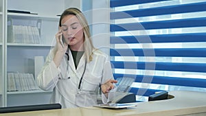 Stressed female medical worker yelling while speaking on phone at hospital reception