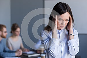 Stressed female worker suffer from headache during office meetin