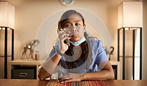 Stressed filipina nurse taking phonecall at home