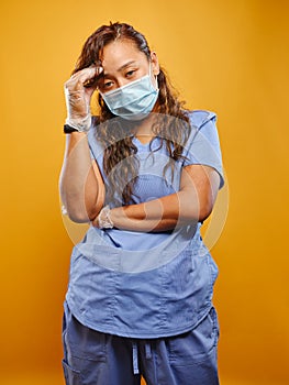 Stressed filipina nurse wearing scrubs and PPE