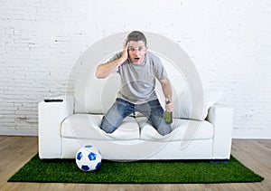 Stressed football fanatic fan watching game on tv nervous in disbelief face as if disaster comes