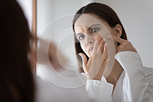 Stressed frowning teenage girl focused on beauty care problem