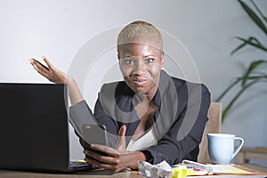 Stressed and frustrated afro American black woman working upset at office laptop computer desk gesturing angry looking at mobile p