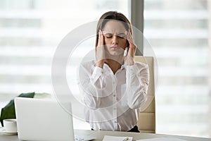 Stressed frustrated female employee feeling headache or migraine