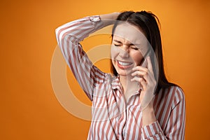 Stressed frustrated young woman holding smartphone, recieved bad news, yellow background