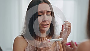 Stressed girl holding pregnancy test mirror place. Woman sad of unplanned baby