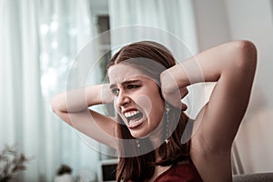 Stressed girl shouting and covering her ears with hands