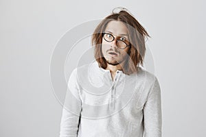 Stressed guy loaded with work and feeling tired. Portrait of good-looking funny man with messy hair and glasses