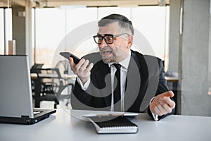 stressed handsome businessman working at desk in modern office shouting at laptop screen and being angry about financial