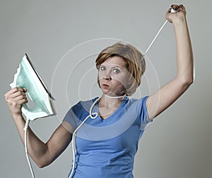 Stressed housewife or maid domestic service woman holding upset iron strangling neck with cable photo