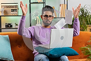 Stressed indian man looking at unpaid bank debt loan, doing paperwork, planning budget, throws bills