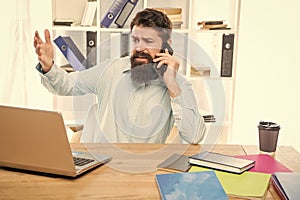 Stressed lawyer yelling on mobile phone working on laptop in office, stress