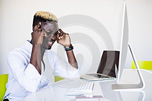 Stressed Male Businessman with head ache sitting with head in Hand At Desk In Office