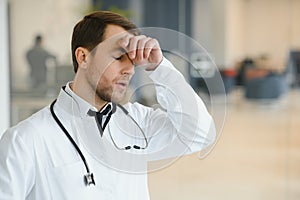 Stressed male doctor. Mid adult male doctor working long hours. Overworked doctor in his office. Not even doctors are