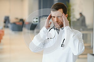 Stressed male doctor. Mid adult male doctor working long hours. Overworked doctor in his office. Not even doctors are