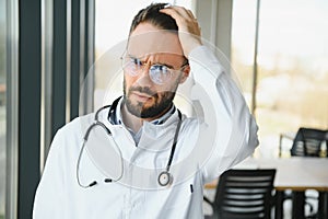 Stressed male doctor. Mid adult male doctor working long hours. Overworked doctor in his office. Not even doctors are